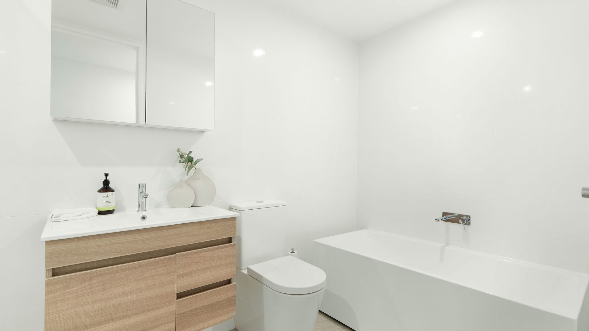 Ein modernes Badezimmer mit einem weißen Waschtisch, einer Toilette und einer Badewanne.