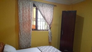 Une chambre avec un lit, une armoire et une fenêtre avec des rideaux.