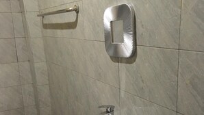 Une salle de bain avec un lavabo sur colonne blanc, un miroir fixé au mur et un porte-serviettes.