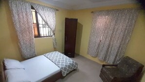 Une chambre à coucher avec un lit, une chaise, une armoire et des rideaux.