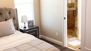 Ein Schlafzimmer mit Bett, Nachttisch, Lampe und einem Schild mit der Aufschrift 'I LOVE US'.
