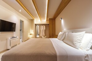 Een moderne hotelkamer met een groot bed, een flatscreen televisie aan de muur, een inloopkast en een badkamer met douche en handdoekhouder.
