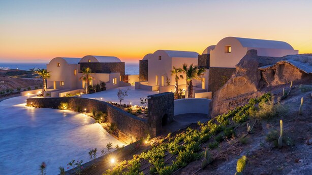 A coastal resort with white buildings, a curved pathway, and palm trees. - Halo Santorini- Living Experience (Santorini)