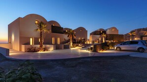A modern building with curved architecture and a car parked in front. - Halo Santorini- Living Experience (Santorini)