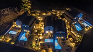 A modern resort with multiple swimming pools, outdoor seating areas, and well-lit pathways. - Halo Santorini- Living Experience (Santorini)
