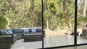 Un espace de vie moderne comprenant un canapé d’angle, une table basse et une cloison en verre.