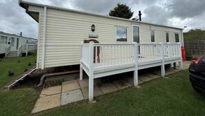 A mobile home with a white exterior, a porch, and a small deck. - Heacham Beach Caravan-sleeps 6-pets Ok-parking (King's Lynn)