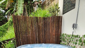 An outdoor hot tub surrounded by bamboo fencing and lush greenery.