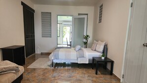 A bedroom with a bed, a bedside table, a nightstand, a wardrobe, and a door leading to a balcony.