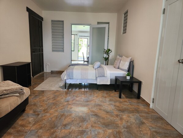 A bedroom with a bed, a bedside table, a nightstand, a wardrobe, and a door leading to a balcony.