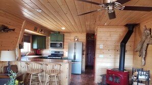 A wooden cabin interior with a kitchen, dining area, and a wood stove. - Charming Lakeview Cabin at Panguitch Lake (Panguitch)