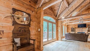 Interior de una cabaña de madera con un espejo grande, un banco, un sofá y un televisor.