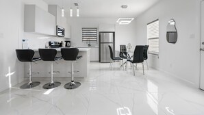 A modern kitchen with a central island, bar stools, and a dining area with chairs.
