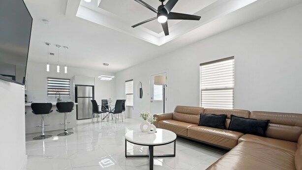 A modern living room with a leather sofa, a coffee table, and a ceiling fan.