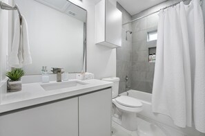 A modern bathroom with a white sink, toilet, and shower area.