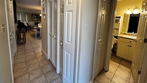 A hallway with a tiled floor, white doors, and a kitchen area with a sink and cabinets.