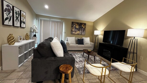A living room with a sofa, a coffee table, a TV, and a fireplace.
