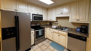 A kitchen with white cabinets, stainless steel appliances, a microwave, oven, dishwasher, and a granite countertop.