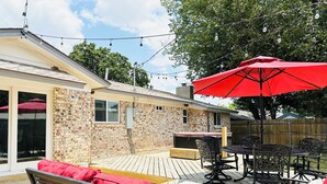 A patio with outdoor furniture, a red umbrella, and a brick wall. - Posh-Ideal Home Rental for Large Fan Group- WALK to AT&T Stadium- 2 King Beds (Arlington)