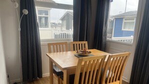 Ein Essbereich mit einem Holztisch und Stühlen, einer Nuss-Schale und Blick auf einen Balkon mit Geländer.