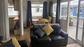 Ein gemütliches Wohnzimmer mit einer schwarzen Ledersofa, einem Holzespeisetisch und einem Balkon mit Blick auf die Nachbarschaft.