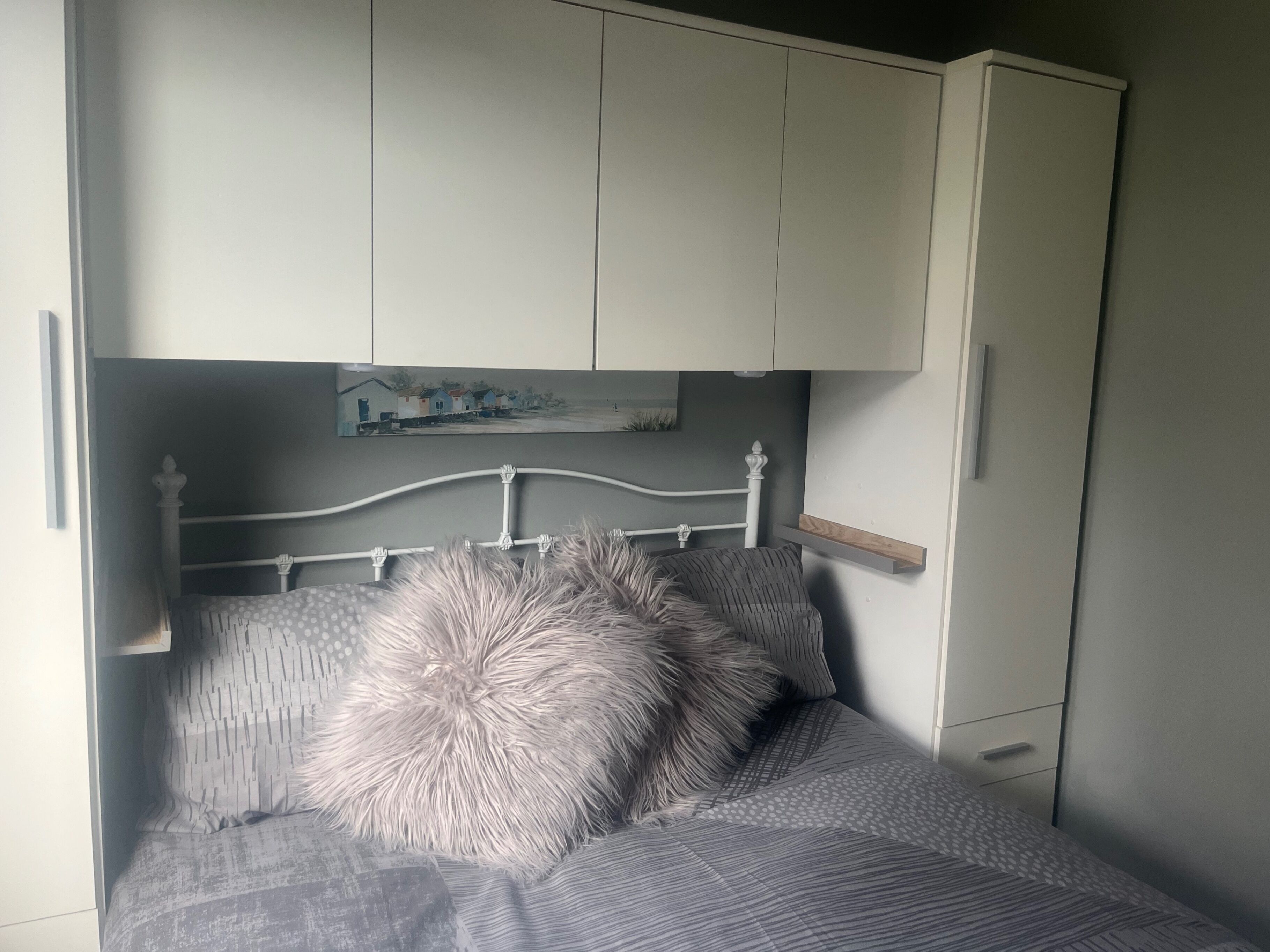 Un dormitorio con una cama, un armario y un cuadro sobre la cama.