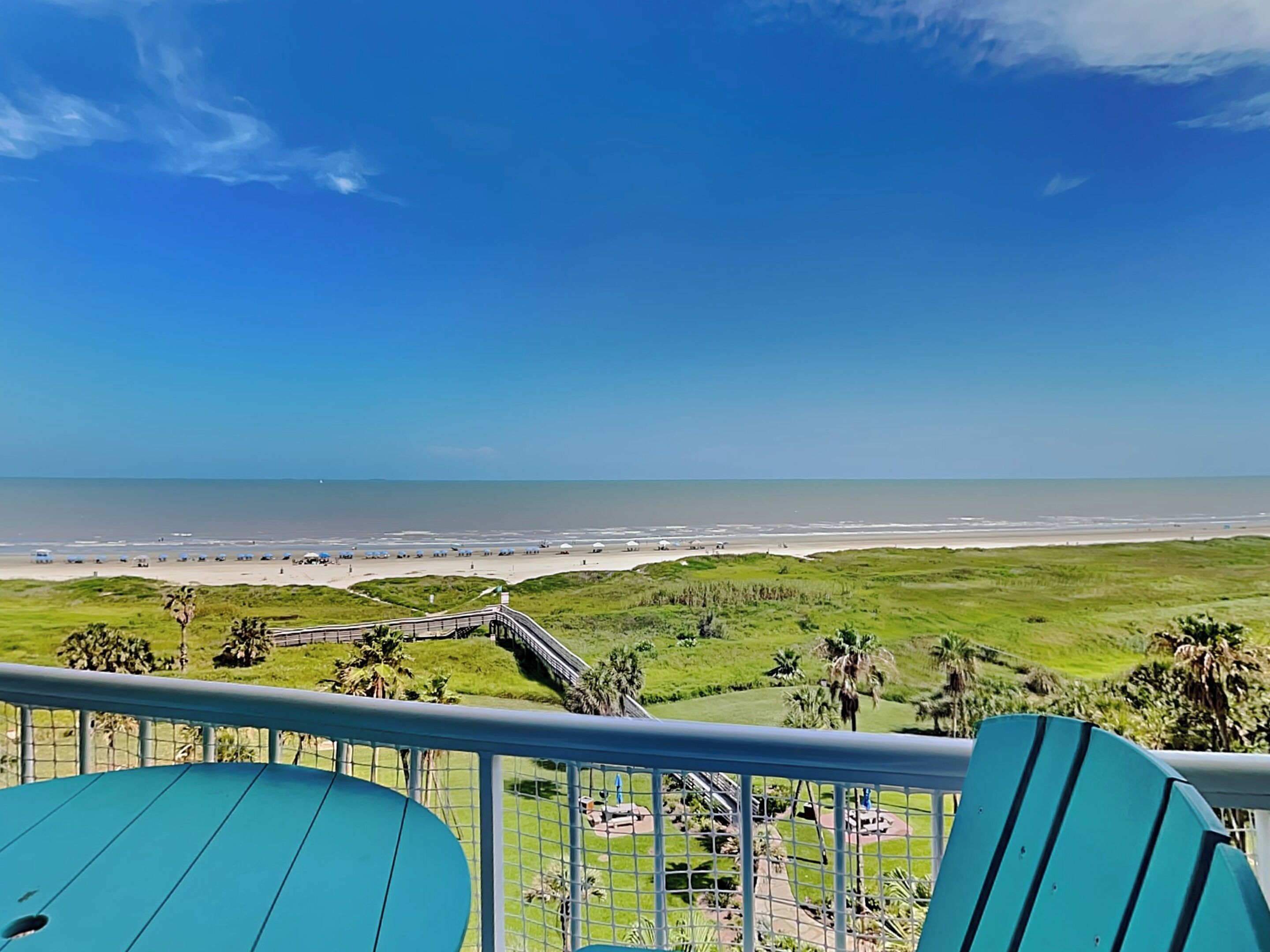 Een balkon met uitzicht op een strand en een promenade.
