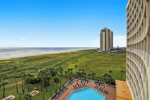 A hotel with a pool, beach view, and palm trees. - Galvestonian by Ryson Vacation Rentals (Galveston)