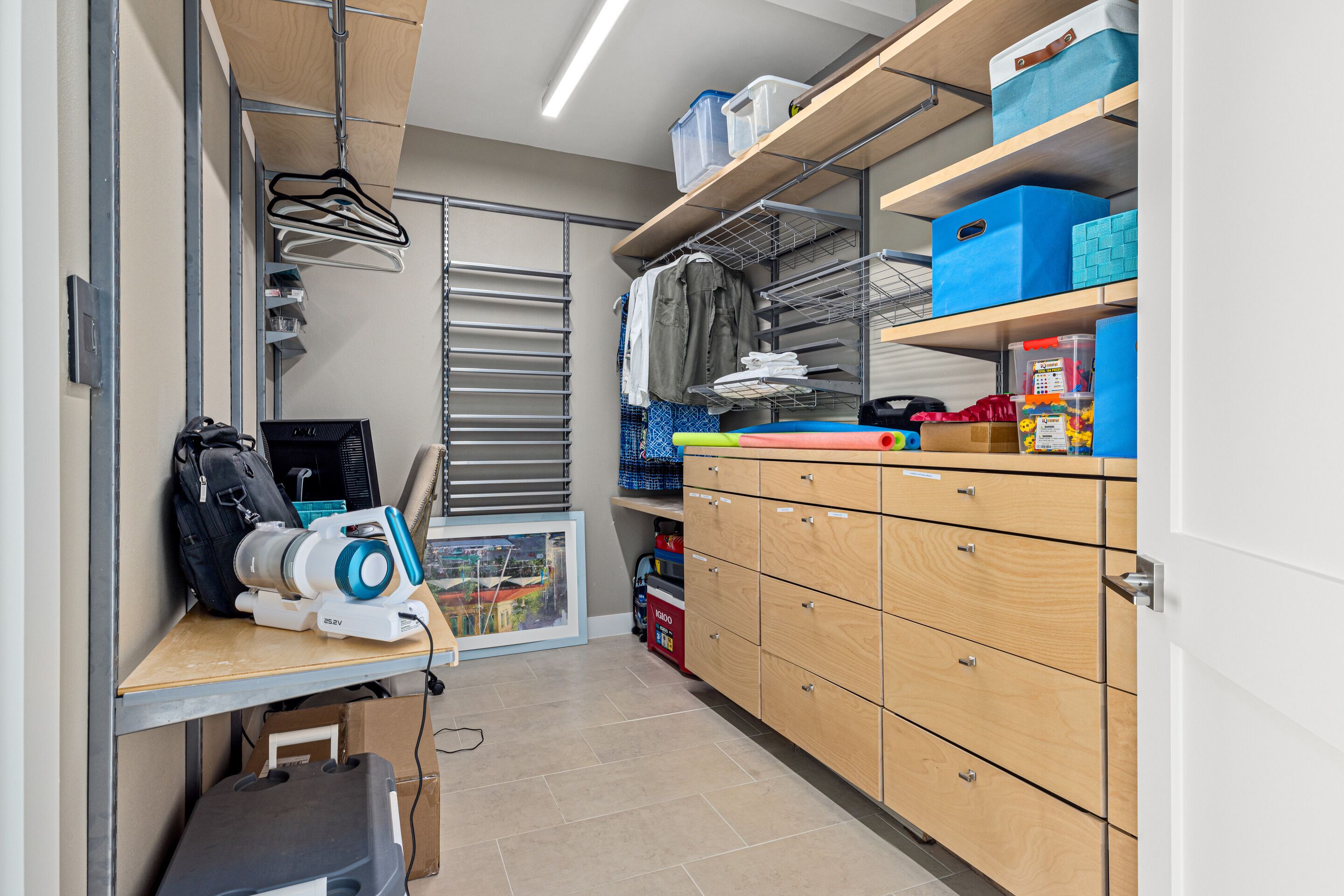 Una habitación bien organizada con escritorio, estanterías y espacios de almacenamiento.