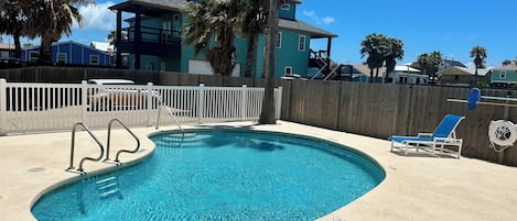 A swimming pool with a 5 ft depth marker, a white fence, and a lifeguard chair.
