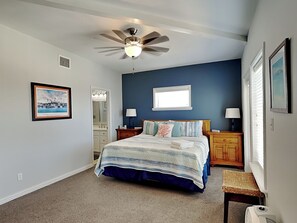 A bedroom with a bed, a ceiling fan, a window, and a nightstand. - Casa Palmera by Silver Sands Vacation Rentals (Port Aransas)