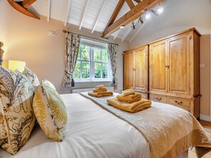 Un dormitorio con cama, ventana con cortinas, armario de madera y radiador.