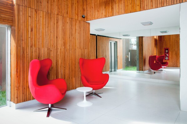 A modern interior with wooden panel walls, red chairs, and a white table. - Dorrego 2415 (Buenos Aires)