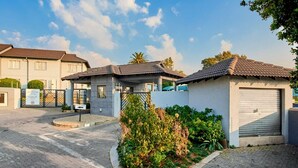 Un quartier résidentiel doté d’une entrée sécurisée, d’un petit jardin et d’un immeuble avec un portail de garage.