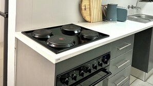 Une cuisine moderne avec des meubles gris, une cuisinière noire et un four encastré.