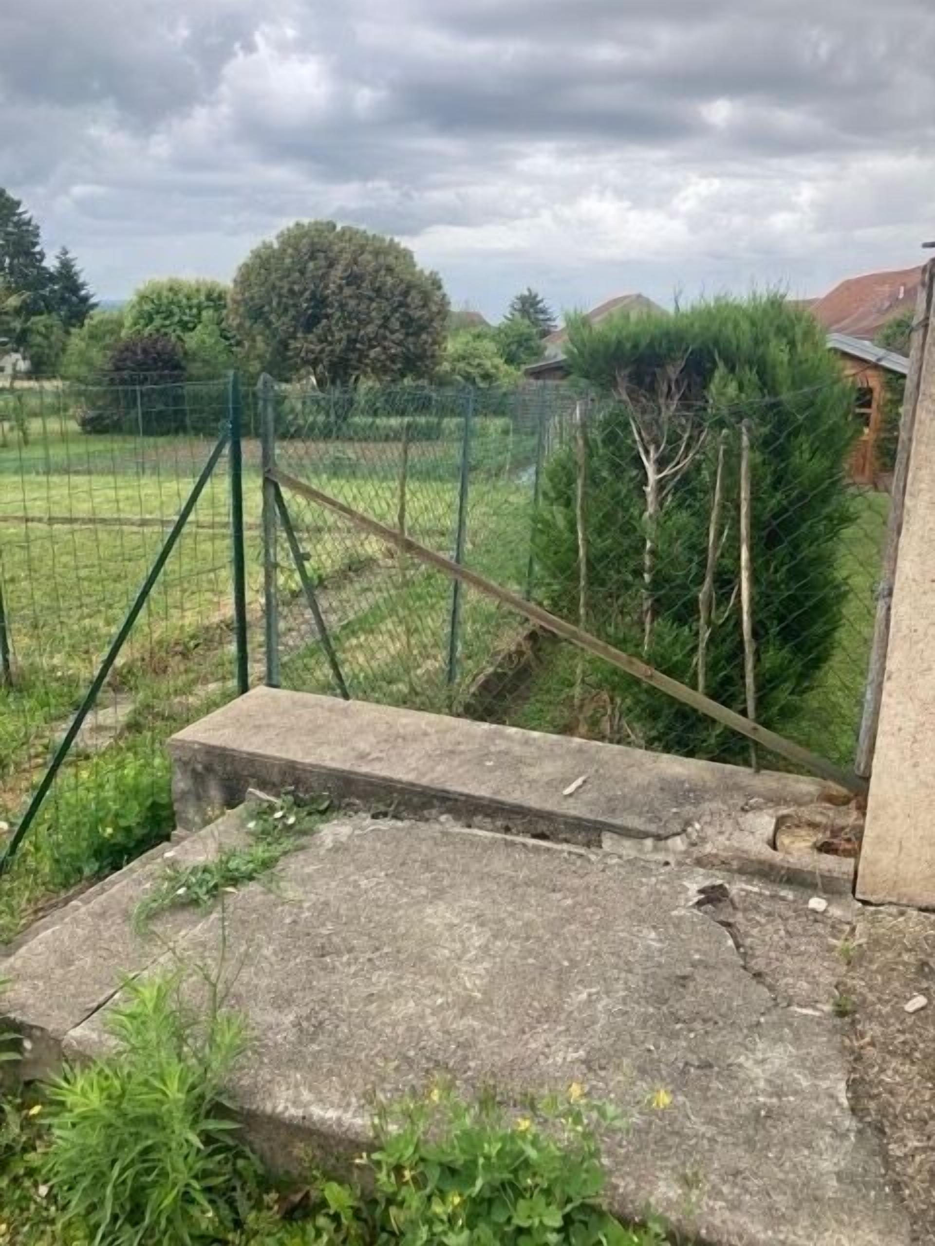 A concrete staircase leading to a fenced area with a metal gate.