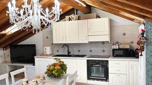 Une cuisine avec des armoires blanches, un lustre, un four à micro-ondes et un évier.
