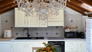 Une cuisine avec des meubles blancs, un lustre et une table à manger décorée de fleurs et de bougies.