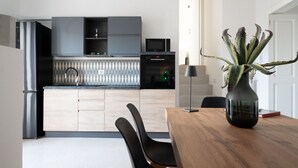 Una cocina moderna con armarios oscuros, un microondas y una zona de comedor con mesa y sillas de madera.