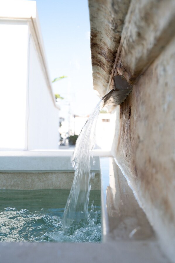 A close-up of a water spout with water flowing into a pool. - Guagnano Suite: Luxury Apartment (Nardò)