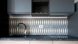 Una cocina moderna con un grifo negro, un salpicadero con diseño de rombos y armarios de madera.