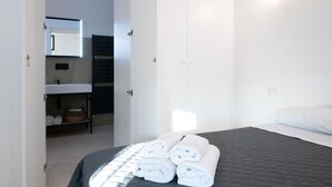 Una habitación de hotel con cama, baño con lavamanos y espejo, y un armario.