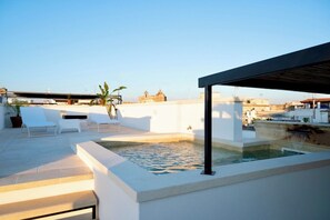 A rooftop terrace with a pool, white lounge chairs, and a pergola. - Guagnano Suite: Luxury Apartment (Nardò)