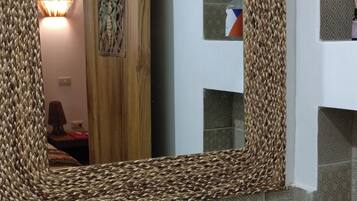 Un baño con un lavabo redondo, un espejo con marco tejido y azulejos estampados.