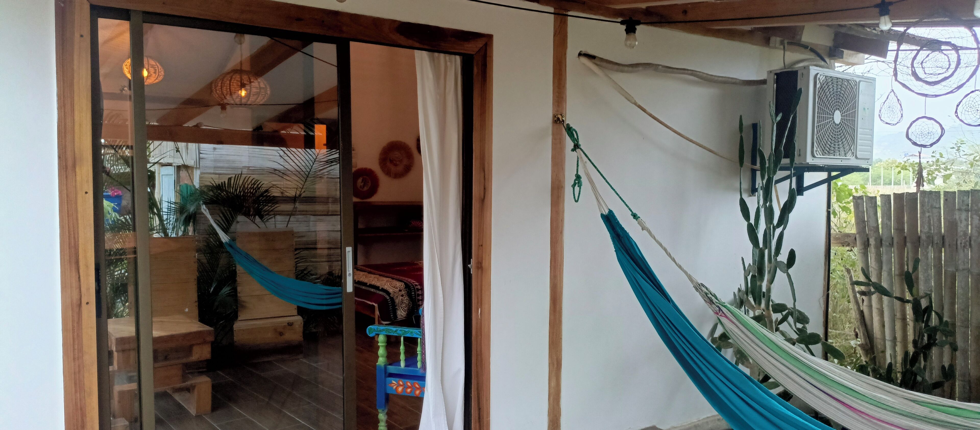 A room with a hammock, a wooden bench, and a glass door leading outside.