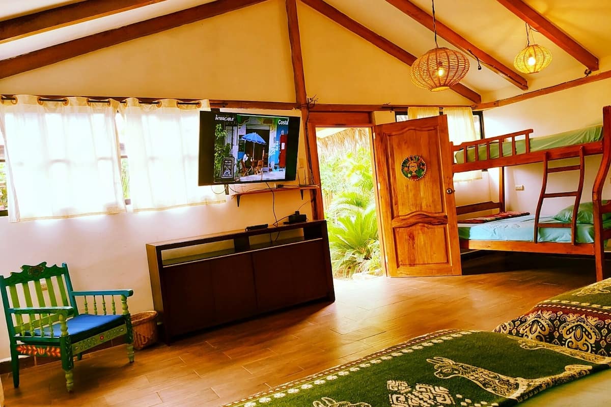 A cozy room with a wooden bunk bed, a television mounted on the wall, a green chair, and a patterned rug.