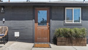 Une maison en bois avec une porte marron, une fenêtre et un paillasson.