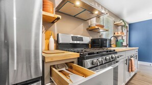 Une cuisine moderne dotée d’appareils électroménagers en acier inoxydable, de plans de travail en bois et de rangements intégrés.