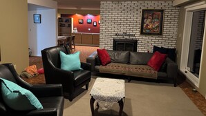 A living room with a fireplace, a dining area with a table and chairs, and a kitchen in the background. - Cozy 2-bedroom apartment with WiFi, AC in amazing Penticton (Penticton)