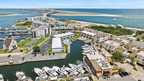 A marina with boats docked, a road curving through the area, and buildings with pools and parking. - Waterfront 2BR Condo *Renovated 2025*  Marina Pool (Orange Beach)